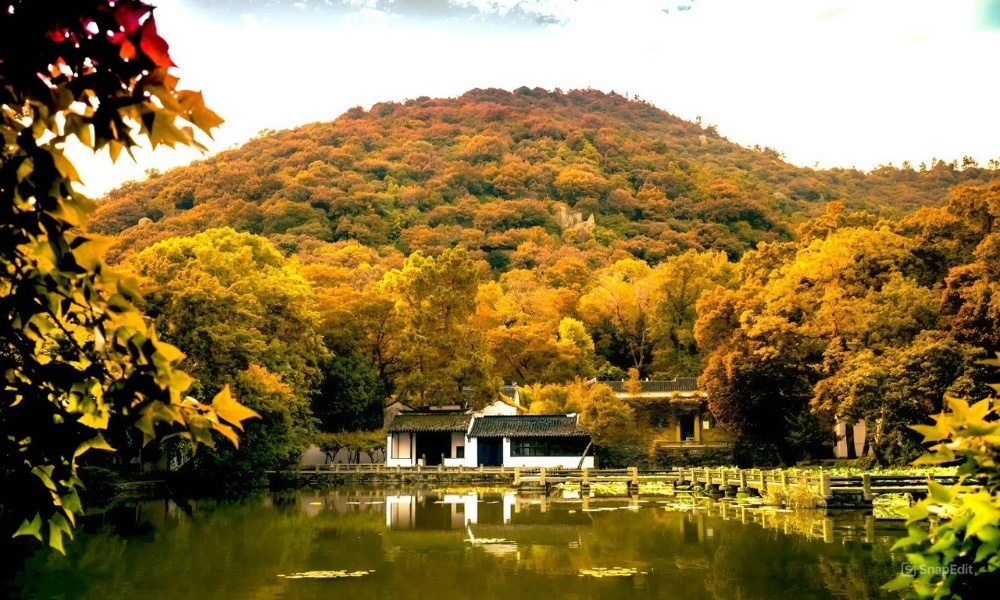 N&uacute;i Cảnh Sơn với những t&aacute;n l&aacute; v&agrave;ng rực rỡ soi b&oacute;ng xuống mặt hồ b&igrave;nh y&ecirc;n ở T&ocirc; Ch&acirc;u